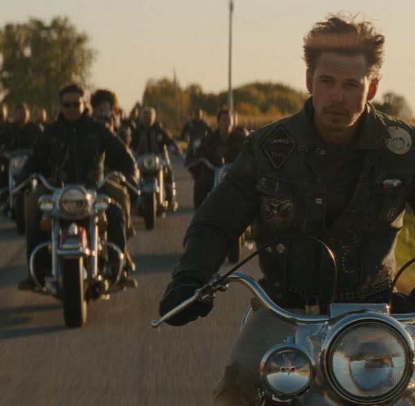 バイクに跨った強者どもが夢のあと『バイクライダーズ / The Bikeriders』、数十年に渡って続いた架空のモーターサイクル・クラブ、ヴァンダルスの栄枯盛衰を描くフィクショナル・ストーリー。 監督は、巨大台風に全てが破壊されるという妄想に取り憑かれた男がシェルターを一人で建造する姿を描いた風変わりなサイコロジカル・スリラー『テイク・シェルター』（2011年）でカンヌ国際映画祭批評家週間でグランプリを受賞したインデペンデント精神溢れる気骨の映画監督ジェフ・ニコルズ。 映画化にあたってオースティン・バトラー、ジョディ・カマー、トム・ハーディ、マイケル・シャノン、ノーマン・リーダスといった旬の演技派や曲者俳優が一堂に介した。 原作は存在せず、原案となったものはアメリカの写真家ダニー・ライアンがバイカーたちの自由放蕩な日々を密着撮影した写真集「The Bikeriders」。 その写真集から強いイメージを抱いたニコルズ監督が後にオリジナル・ストーリーを書き上げた。 長年に渡り、映画化を夢想するニコルズに対し、本作にも登場する同監督の常連俳優マイケル・シャノンは、そんな話、映画化できるわけがないと監督の熱き想いは否定的に受け止められてきたという。 60年代から70年代にかけての激動のアメリカ社会で自由で破天荒に生きたアウトローたちの姿を描いた本作が現代に問うこととは？、オースティン・バトラー演じるベニーのリアル過ぎるタトゥーは実はフェイク、バイクライダーズ、The Bikeriders、ジェフ・ニコルズ、オースティン・バトラー、ジョディ・カマー、トム・ハーディ、マイケル・シャノン、マイク・ファイスト、ノーマン・リーダス、ボイド・ホルブルック、デイモン・ヘリマン、ボー・ナップ、エモリー・コーエン、カール・グルスマン